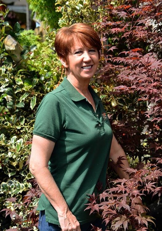 karen-edited-web72-555 A woman in a green shirt standing in front of bushes.