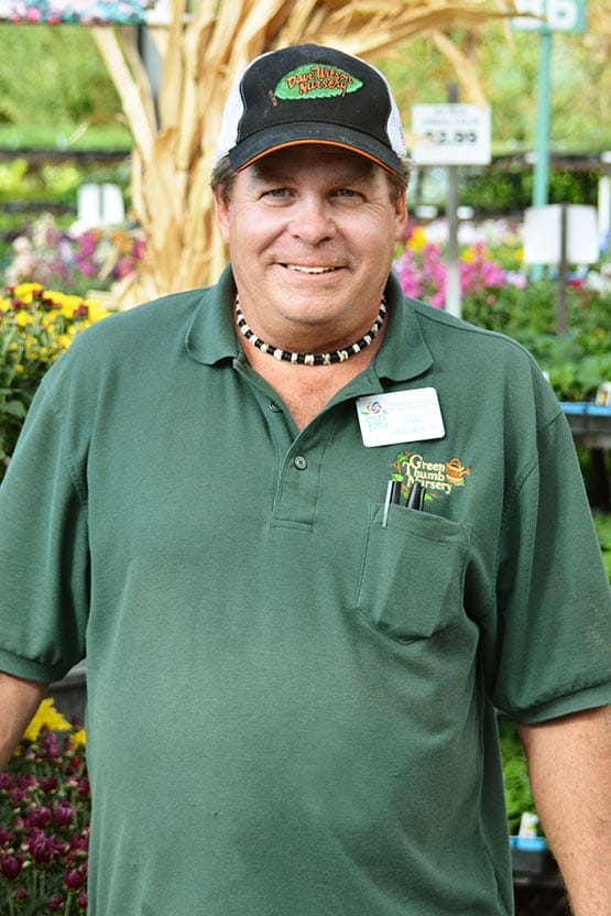 A man in a green shirt standing in a garden center.