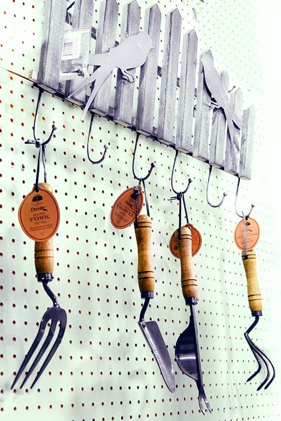 A pegboard with garden tools hanging on it.