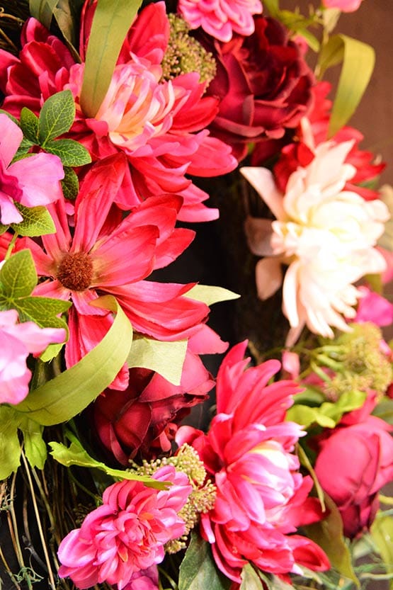 A wreath with pink flowers and green leaves.