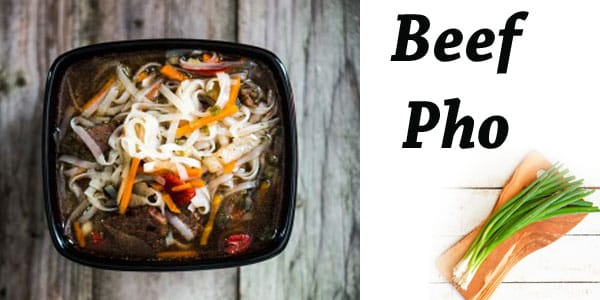 A bowl of beef pho on a wooden table in a Southern California garden center.