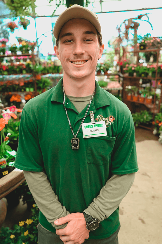 A man in a green shirt browsing at a flower shop.