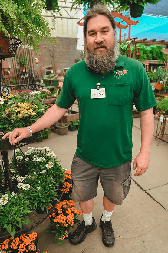 A man with a beard standing in front of a garden center.