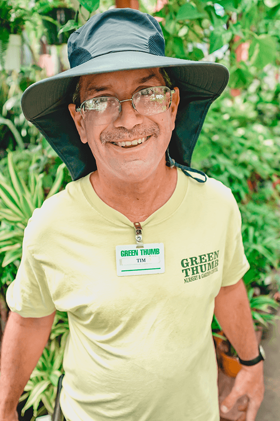A man in a hat standing in a garden nursery center.