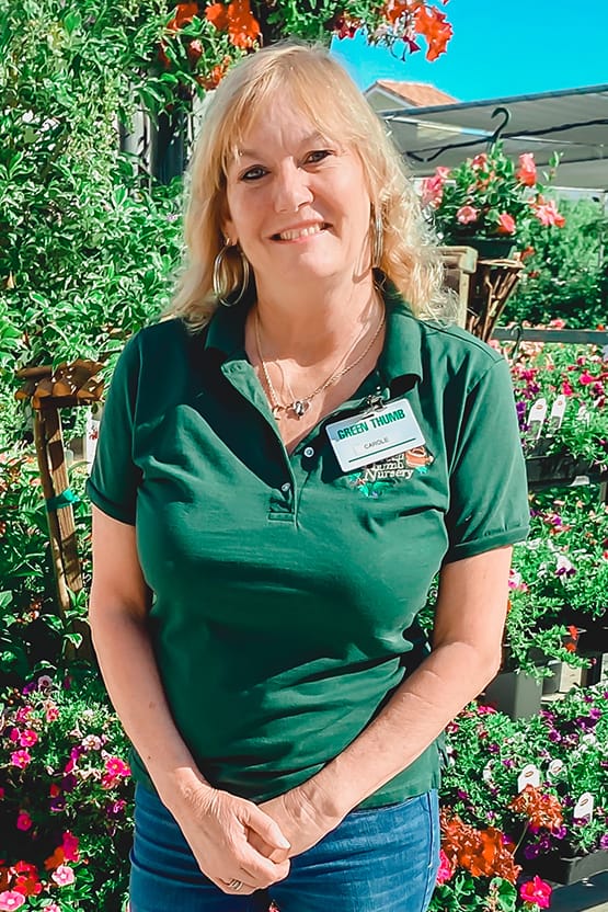 A woman in a green shirt amid lush plants at the best nursery near me.