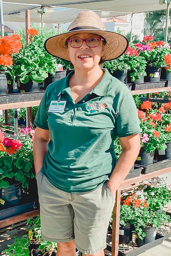 A woman in a hat standing in front of potted plants at the best garden center near me.