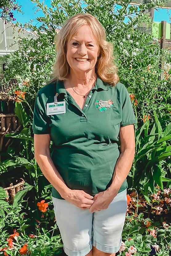 A woman standing in front of a garden.