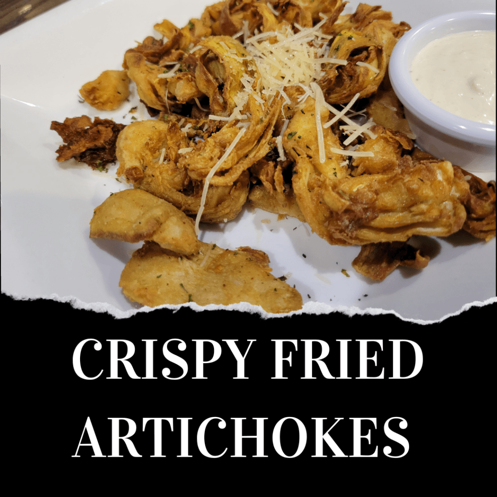 A plate of crispy fried artichokes topped with shredded cheese, served with a side of dipping sauce. Text reads "CRISPY FRIED ARTICHOKES.