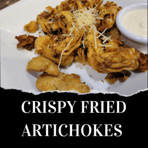 A plate of crispy fried artichokes topped with shredded cheese, served with a side of dipping sauce. Text reads "CRISPY FRIED ARTICHOKES.