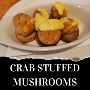 A plate of crab stuffed mushrooms topped with melted cheese, served on a white oval dish.