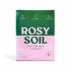 A green and pink bag labeled "Rosy Soil Indoor Potting Mix," with icons indicating it is professionally blended, peat and synthetic free, and each bag captures CO2.