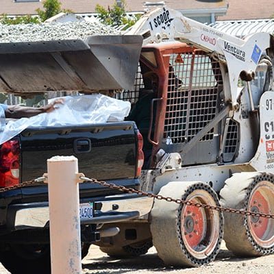 bulk-soil A man loading bulk soil into the back of a pick up truck with heavy machinery.