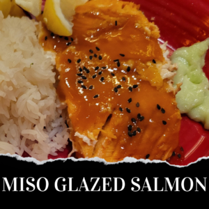 A plate of miso-glazed salmon served with white rice and a dollop of wasabi.