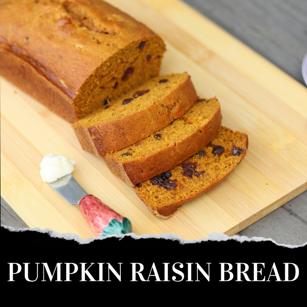 Sliced loaf of pumpkin raisin bread on a wooden board, with a butter knife and a dab of butter beside it.