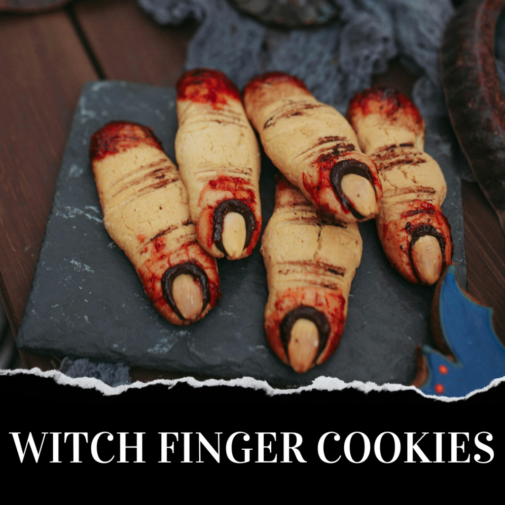 A slate plate with five witch finger-shaped cookies, featuring almond nails and red icing details. Text below reads "Witch Finger Cookies.