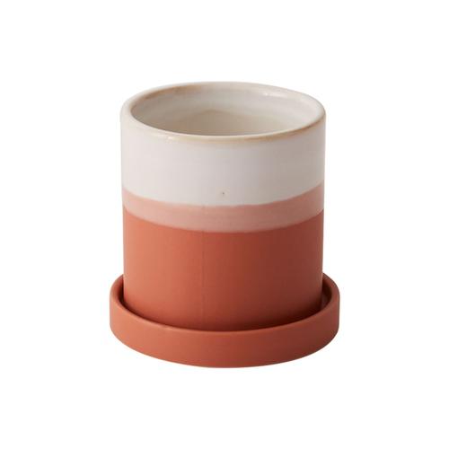 A ceramic cup with a white and terracotta color scheme, sitting on a matching saucer.