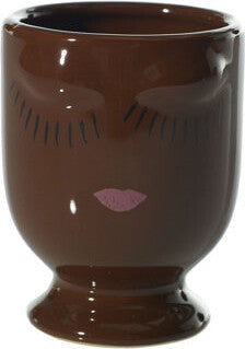 A brown ceramic cup with a face design, featuring closed eyes and pink lips.
