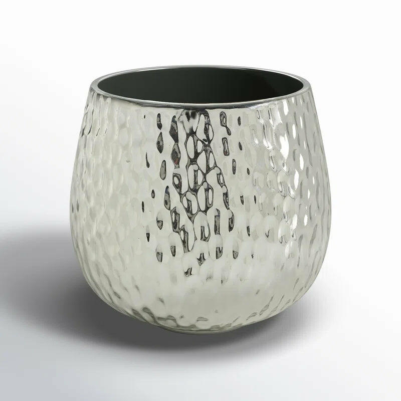 A textured silver metal vase with a rounded shape and an open top, featuring a dark interior.