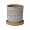 Beige and light brown ceramic planter with a matching saucer, featuring a decorative heart pattern around the middle.