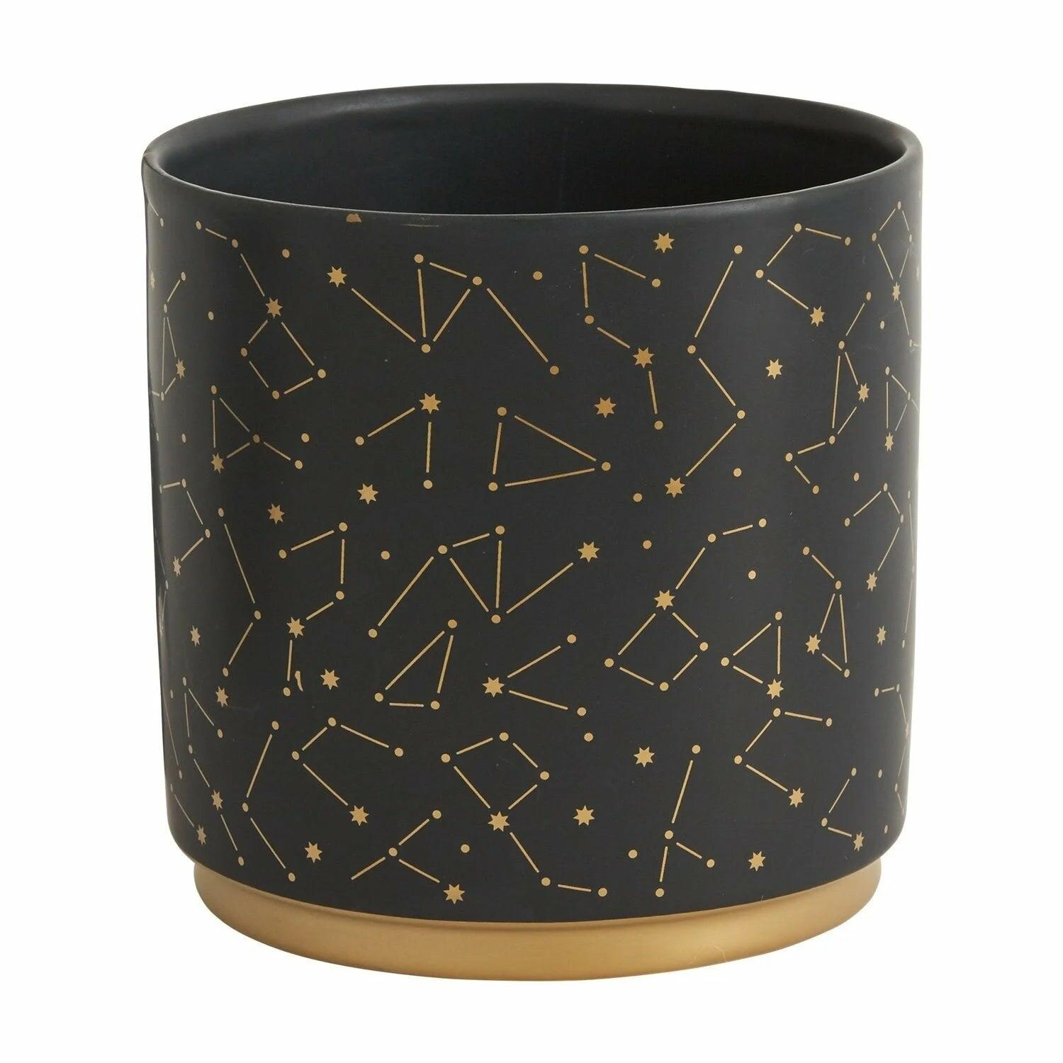 A black cylindrical planter with gold constellation patterns on its surface.