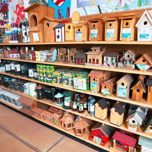 bird feeders 2 Store shelves displaying various wooden birdhouses and bird feeders, along with gardening supplies.
