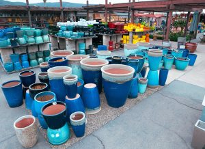 san marcos pottery 3 Display of various blue and teal ceramic pots of different sizes and shapes at an outdoor retail area.