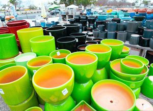 san marcos pottery Various colorful ceramic plant pots displayed outdoors in rows.