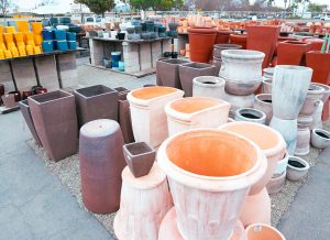 san marcos pottery 4 Outdoor display of various ceramic and clay pots in different shapes and sizes, organized on a paved surface.