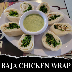 A plate of sliced chicken wraps with greens, arranged around a bowl of green dipping sauce, labeled "BAJA CHICKEN WRAP.